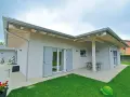 Esterni di case moderne ad un piano con tetto spiovente, ampie vetrate e un patio con tavolo.