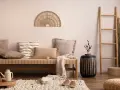 Un accogliente salotto bohemien con divano in paglia, cuscini morbidi, una scala in bambù e decorazioni naturali.