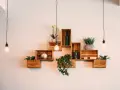Come posizionare i cubi a muro: una composizione creativa con piante, bottiglie e decorazioni su mensole di legno.