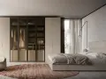Camera da letto moderna con letto, armadio a vista e poltrona. Ottimi spunti su come disporre i mobili in camera da letto per un look elegante.