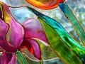 Dettaglio di un fiore dipinto su vetro, con petali viola e verdi vibranti. Un'ispirazione per il **dipinto su vetro fai da te**.