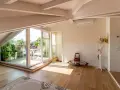 Luminoso sottotetto con travi a vista e un terrazzo fiorito. Idee sottotetto molto basso per sfruttare ogni angolo.