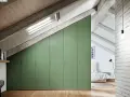 Armadio mansarda fai da te, soluzione salvaspazio con ante verdi che seguono la pendenza del tetto, illuminato da lucernario.
