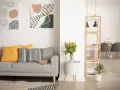 Soggiorno moderno con divano grigio, cuscini gialli e decorazioni astratte. Si nota la differenza tra ammobiliato e arredato: qui, ogni elemento è scelto con cura per creare un ambiente accogliente.