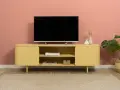 Un mobile giallo vivace con un televisore, riviste e vasi crea una parete tv particolare.