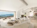Soggiorno luminoso con vista mare, perfetto per l'arredo case al mare. Divani bianchi, camino moderno e tavolo da pranzo per godersi il panorama.