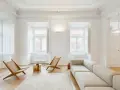 Soggiorno minimalista con divano chiaro, sedie in legno e tavolino dorato. Un esempio di come un consulente d'arredo può creare un ambiente luminoso e accogliente.