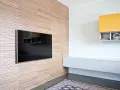 Pannellatura a righe per rivestire una parete interna in modo economico, con TV incassata e mensole moderne.