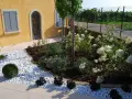 Giardini idee da copiare: un angolo con ghiaia bianca, arbusti verdi e ortensie bianche.
