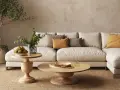 Un accogliente soggiorno con un divano componibile color crema, tavolini in legno e piante. L'arredamento stile contemporaneo crea un'atmosfera rilassante.