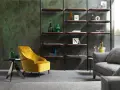 Un comodo angolo lettura con poltrona gialla, tavolino nero e libreria a parete con oggetti decorativi.