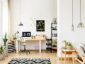 Un moderno angolo studio con scrivania in legno, computer, piante e un divano accogliente.