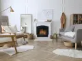 Un soggiorno accogliente con camino acceso, poltrone in legno, divano grigio e tappeti soffici. Perfetto per una casa cozy.