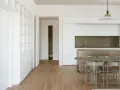 Interni moderni con cucina a isola, tavolo e sedie. Ampia libreria a muro, segno di un **cambio destinazione d'uso da magazzino ad abitazione**.
