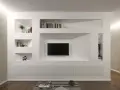 Una moderna parete in cartongesso con nicchie per libri, TV e decorazioni.