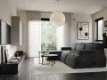 Soggiorno in una casa stile moderno contemporaneo, con divano angolare grigio, tavolini neri, TV a parete e grande lampada sferica.