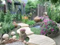 Percorso sinuoso in legno tra fiori vivaci e vasi in terracotta, con elementi decorativi che evocano idee giardino zen.
