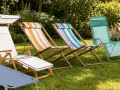 Diversi sdraio da giardino lettino colorati e bianchi, disposti sull'erba verde, pronti per il relax estivo.