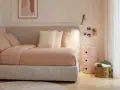 Un angolo letto con biancheria a quadri, cuscini morbidi e un quadro astratto. L'ambiente è accogliente, perfetto per creare camere aesthetic.