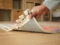 Mano che solleva un tappeto per mostrare il suo retro antiscivolo, perfetto per progetti fai da te e per evitare che scivoli.