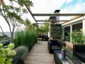 Un terrazzo moderno e accogliente, perfetto per arredare con stile. Mobili in rattan nero, un giardino verticale rigoglioso e piante verdi creano un'oasi urbana.