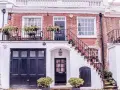 Idee case di campagna esterni: scala bianca fiorita, balcone con piante, porta scura e garage.