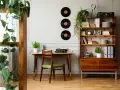 Scrivania con macchina da scrivere e sedia verde, libreria con dischi in vinile e piante. Perfette idee arredamento vintage per un angolo studio.