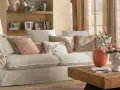 Divano bianco con cuscini decorati, lampada e tavolino in legno creano un'atmosfera di **stile cozy**.
