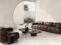 Salotto moderno con divano e poltrona in pelle marrone, tavolino in legno scuro e vista su un giardino interno. L'ambiente evoca la serenità di una casa provenzale.