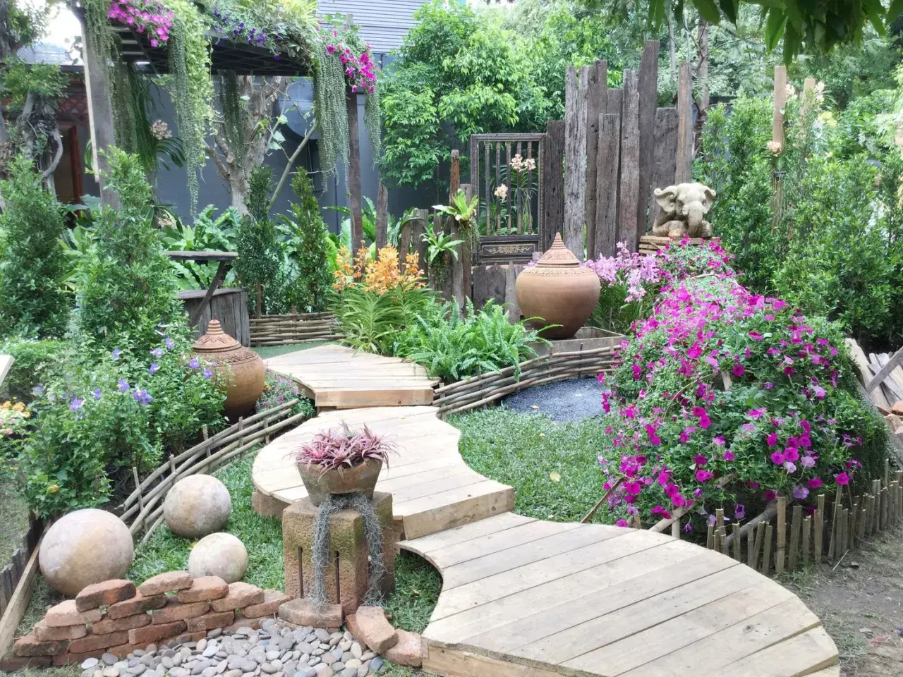 Percorso sinuoso in legno tra fiori vivaci e vasi in terracotta, con elementi decorativi che evocano idee giardino zen.