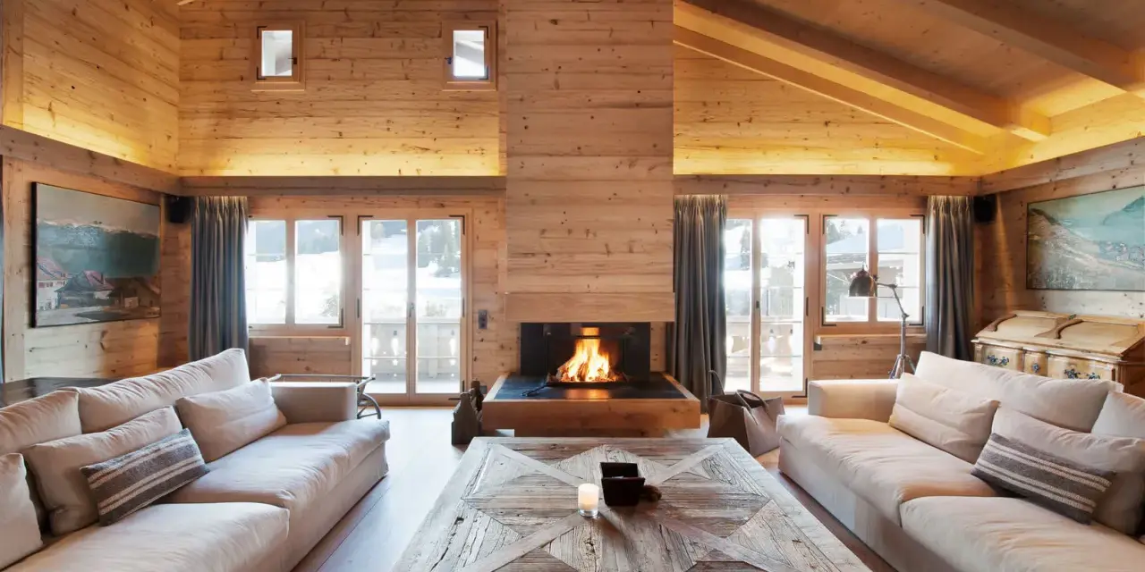 Un **soggiorno caldo e accogliente** con camino scoppiettante, divani comodi e soffitto in legno.