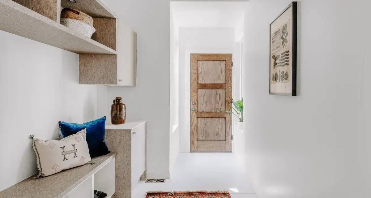 Ingresso accogliente con panca, cuscini e un tappeto persiano. Idee per decorazioni porte interne fai da te ispirate a questo stile.