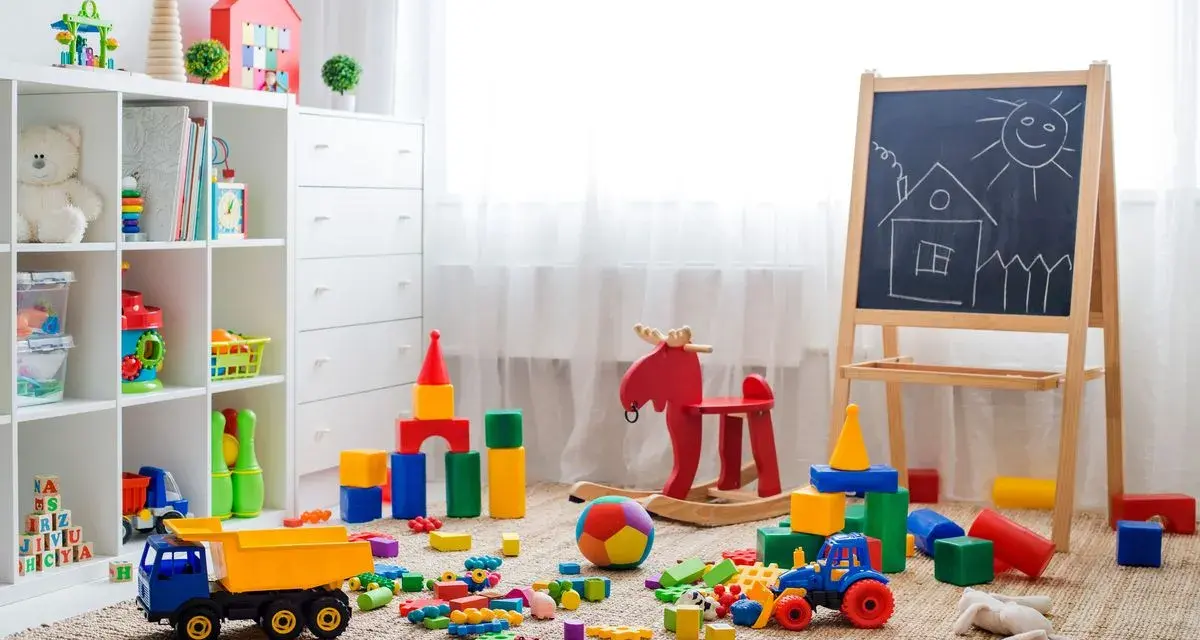 Un angolo pieno di giochi colorati, blocchi, un camioncino, un cavallo a dondolo e una lavagna: perfette idee stanza giochi bambini per stimolare la creatività.