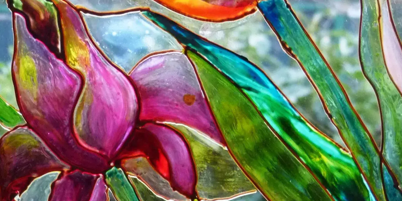 Dettaglio di un fiore dipinto su vetro, con petali viola e verdi vibranti. Un'ispirazione per il **dipinto su vetro fai da te**.