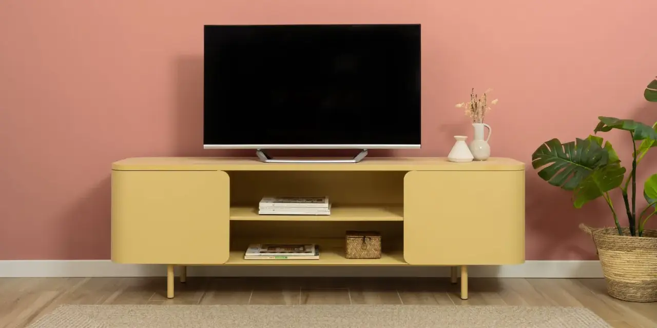 Un mobile giallo vivace con un televisore, riviste e vasi crea una parete tv particolare.