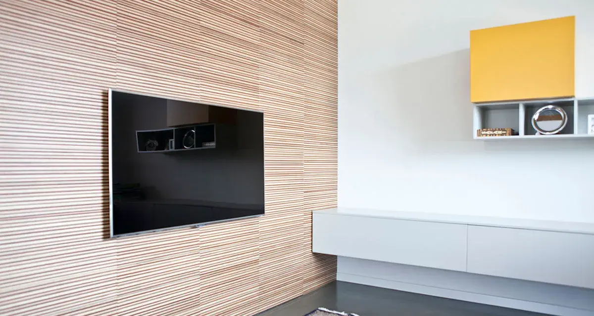Pannellatura a righe per rivestire una parete interna in modo economico, con TV incassata e mensole moderne.