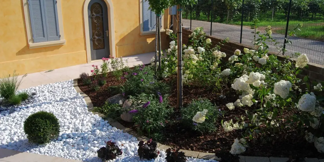 Giardini idee da copiare: un angolo con ghiaia bianca, arbusti verdi e ortensie bianche.