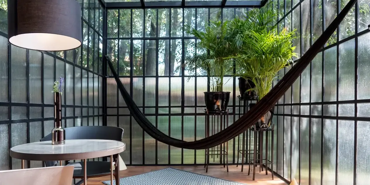 Veranda piccola arredata con amaca, piante e un tavolino. Idee per arredare una veranda piccola con stile e comfort.