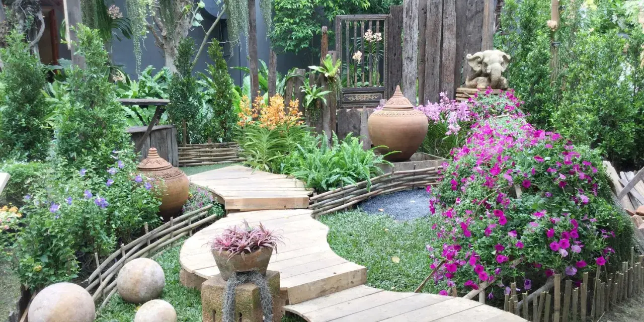 Percorso sinuoso in legno tra fiori vivaci e vasi in terracotta, con elementi decorativi che evocano idee giardino zen.