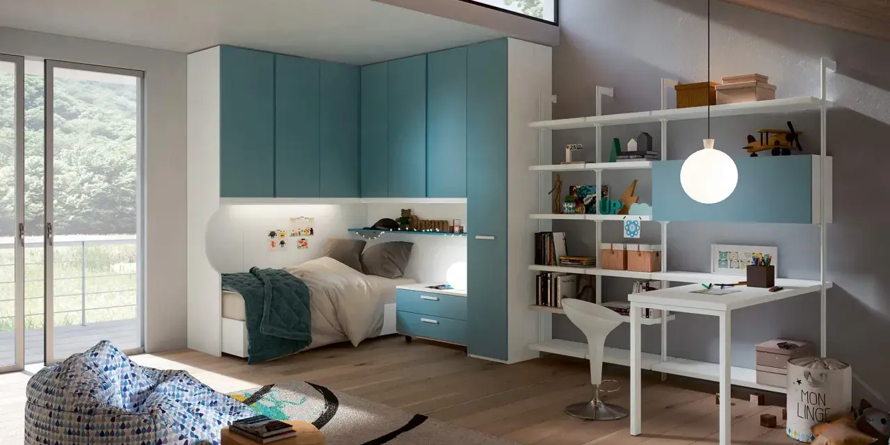 Accogliente camera ragazzo con letto, armadi blu, scrivania e pouf.