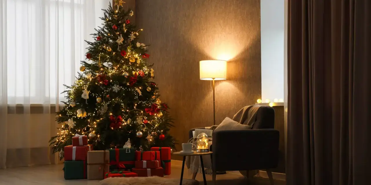 Un accogliente soggiorno con un **albero di Natale stile scandinavo** illuminato, circondato da regali. Una poltrona invitante e una lampada creano un'atmosfera calda.