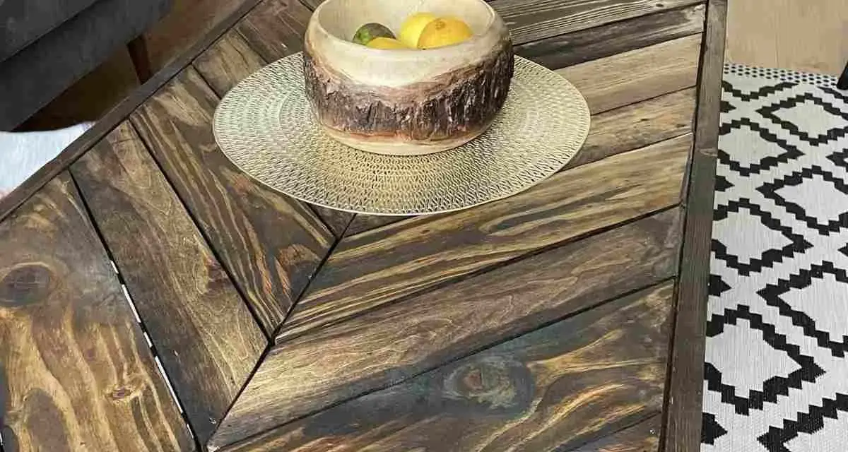 Tavolo con pallet fai da te, con un cesto di frutta in legno e un tappeto geometrico.