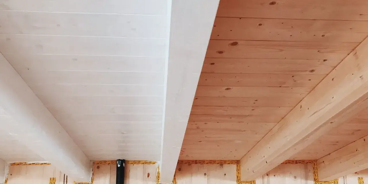 Soffitto perlinato sbiancato con travi a vista in legno naturale. Un contrasto di finiture che crea un ambiente caldo e luminoso.
