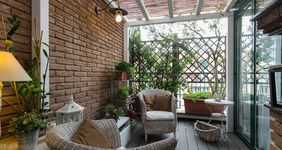 Accogliente veranda piccola con mobili in vimini, piante verdi e un pergolato in bambù. Perfetta per creare un angolo relax.