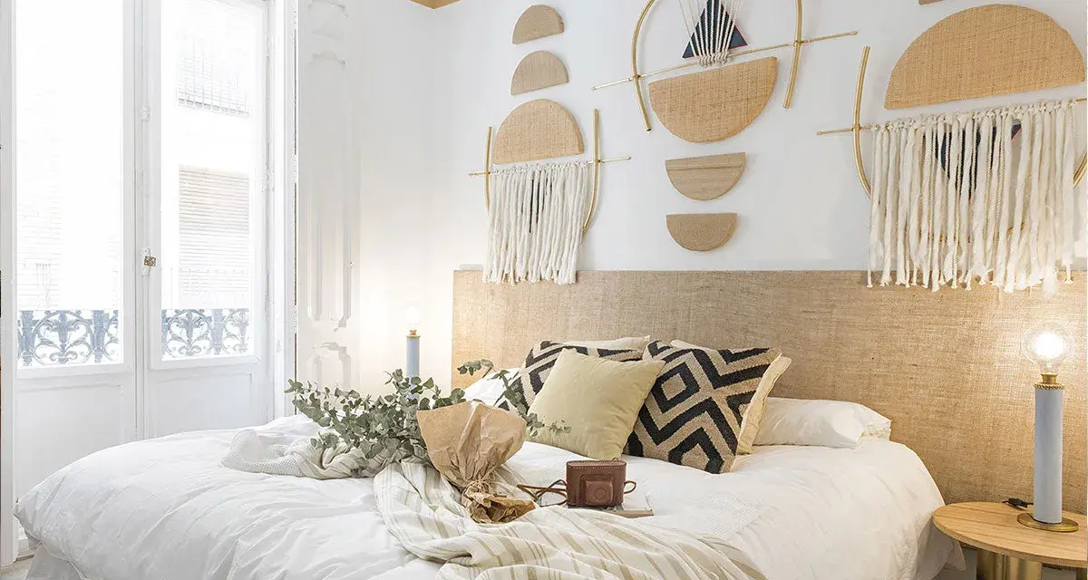 Accogliente camera da letto stile boho con decorazioni murali geometriche, tessuti naturali e un letto invitante.