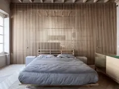 Camerette con separè in legno che creano un ambiente caldo e moderno. Letto matrimoniale con biancheria grigia e comodini bianchi.