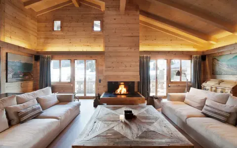 Un **soggiorno caldo e accogliente** con camino scoppiettante, divani comodi e soffitto in legno.