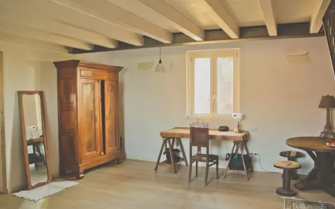 Arredamento casa di campagna: armadio antico in legno, specchio, scrivania rustica con sedia, tavolino rotondo e lampada a forma di Torre Eiffel.