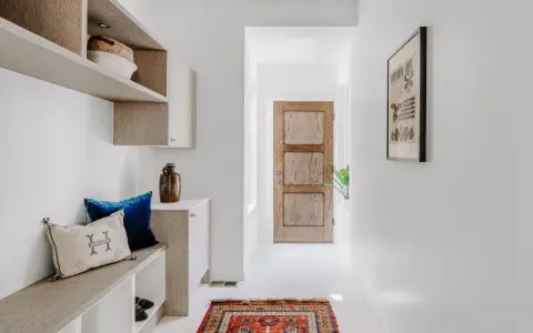 Ingresso accogliente con panca, cuscini e un tappeto persiano. Idee per decorazioni porte interne fai da te ispirate a questo stile.