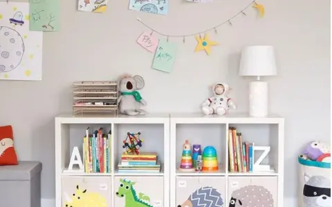 Soluzione creativa per come sistemare i giochi in salotto: scaffali bianchi con contenitori decorati e libri ordinati.